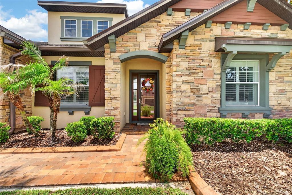 The exterior of a house features stone siding, a brick walkway, and a front entrance — 4209 FOXHOUND DRIVE, CLERMONT, FL