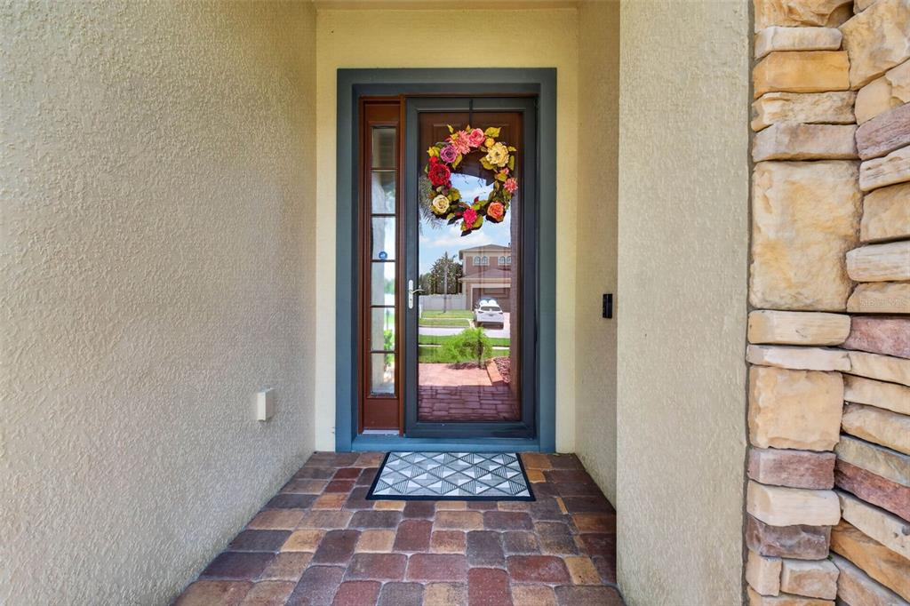 A front entryway features a paved porch, a storm door with a wreath, and stone siding — 4209 FOXHOUND DRIVE, CLERMONT, FL