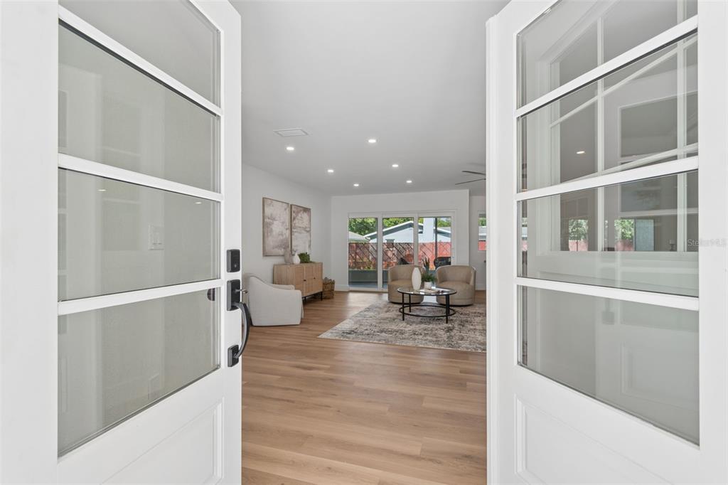 A view through open double doors into a living room with light wood flooring — 12805 KIMBERLY OAKS CIRCLE, LARGO, FL