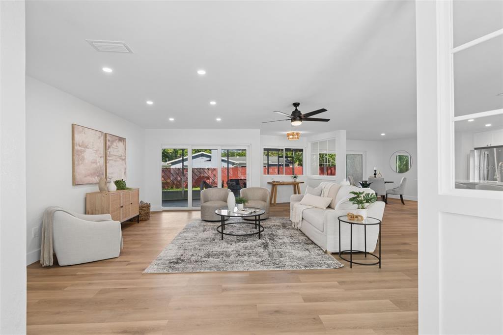 A bright, open-concept living room features light wood floors, a white sofa, and sliding doors — 12805 KIMBERLY OAKS CIRCLE, LARGO, FL