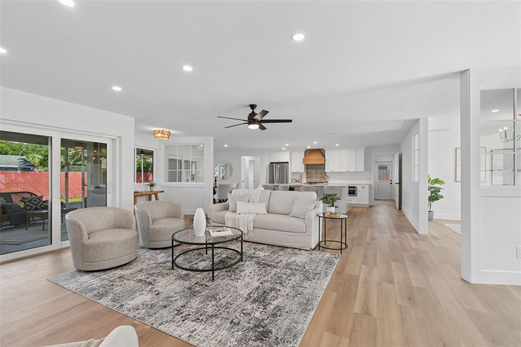 A bright, open-concept living room and kitchen featuring light wood flooring and neutral furniture — 12805 KIMBERLY OAKS CIRCLE, LARGO, FL