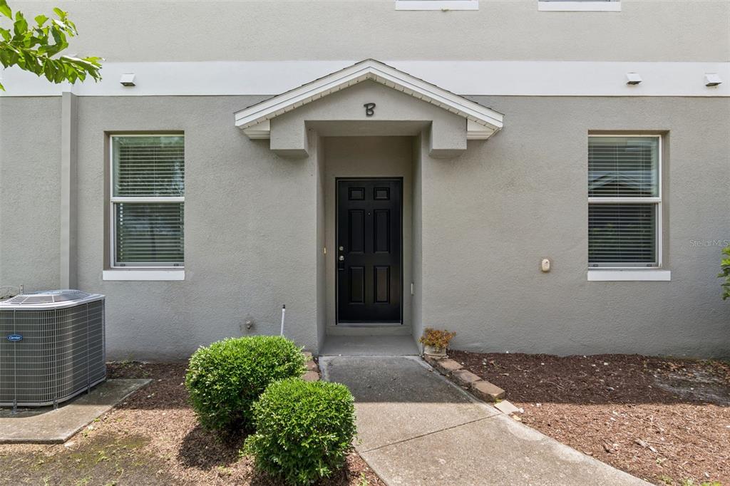 The exterior of a gray townhouse features a black front door marked with a B — 6558 S GOLDENROD ROAD UNIT 78B, ORLANDO, FL