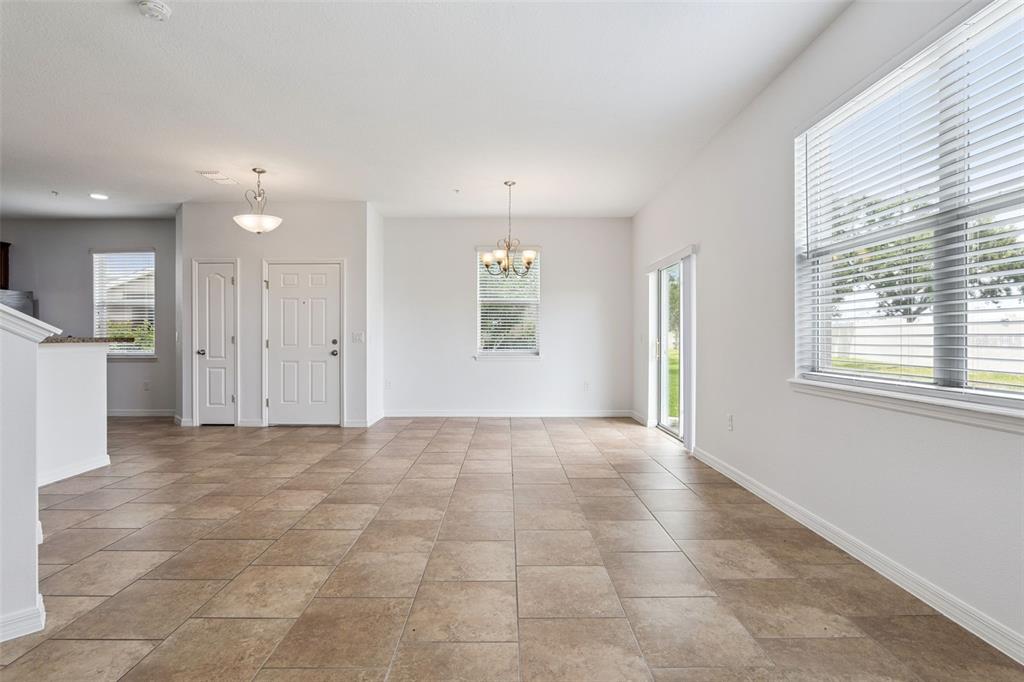 An empty dining area features beige tile flooring, white walls, a chandelier, and sliding doors — 6558 S GOLDENROD ROAD UNIT 78B, ORLANDO, FL