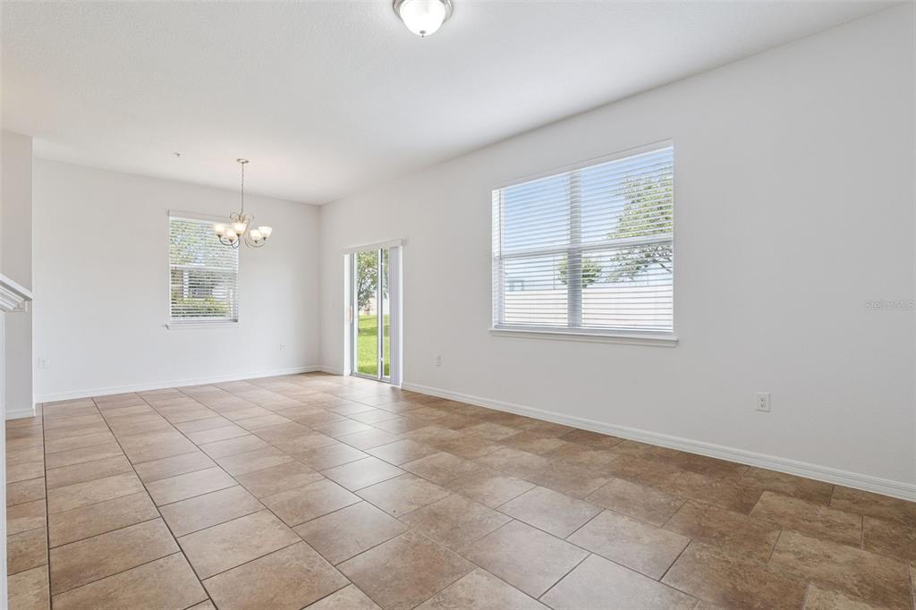 An empty room with tan tile flooring, white walls, a chandelier, and a sliding door — 6558 S GOLDENROD ROAD UNIT 78B, ORLANDO, FL