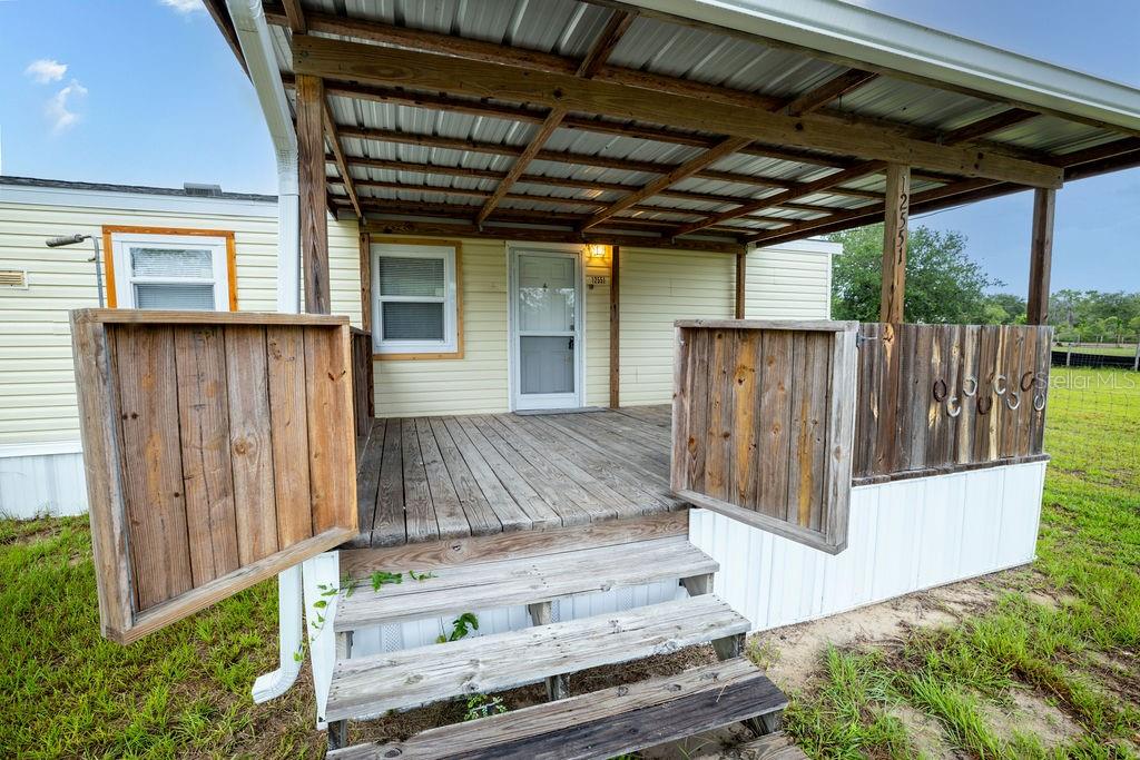A wooden deck with a covered porch and stairs leads to the front door — 12551 NE 14TH STREET, WILLISTON, FL