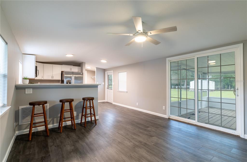 A kitchen with a breakfast bar and stools opens into a living area with sliding doors — 12551 NE 14TH STREET, WILLISTON, FL