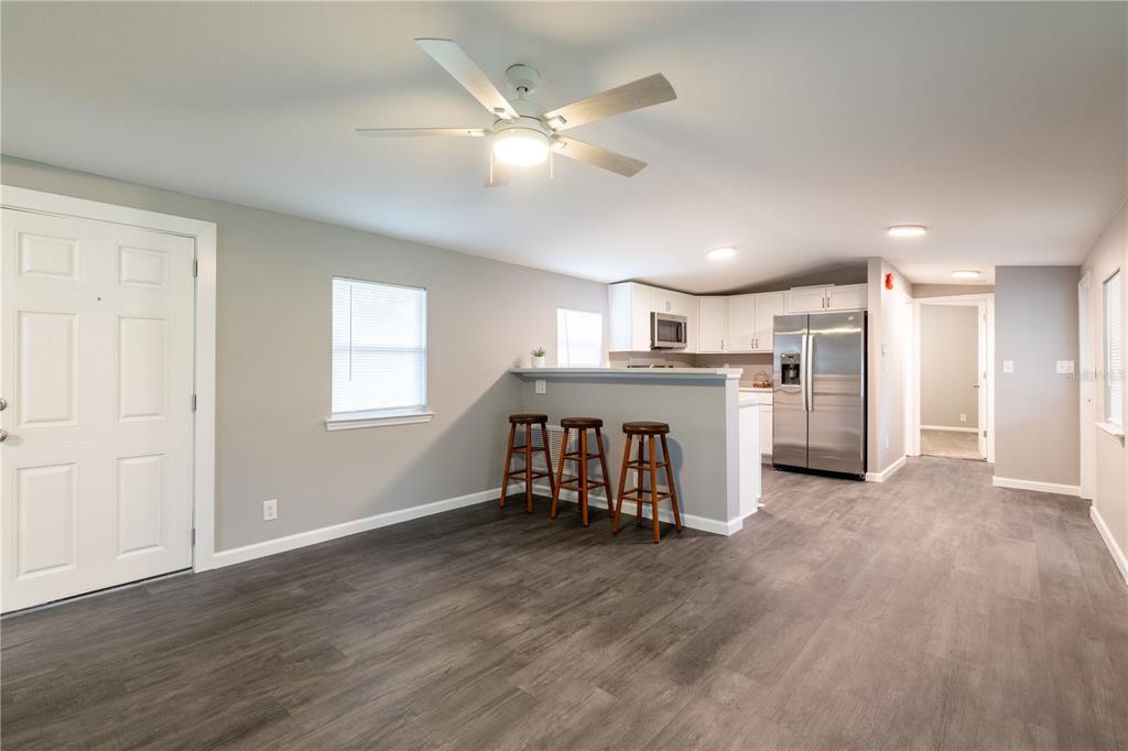 A kitchen with white cabinets and stainless steel appliances opens to a living area — 12551 NE 14TH STREET, WILLISTON, FL