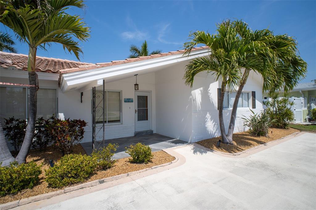 A white single-story house with a covered entryway, palm trees, and a concrete driveway — 2220 E VINA DEL MAR BOULEVARD, ST PETE BEACH, FL