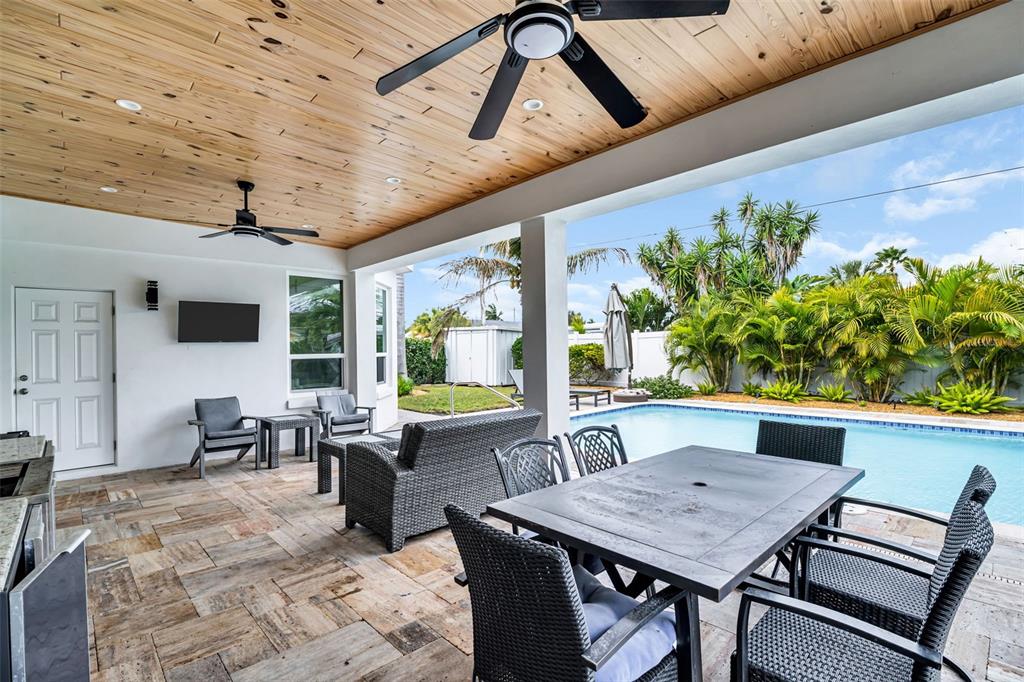 A covered outdoor patio features a wood-paneled ceiling, stone flooring, and a swimming pool — 2220 E VINA DEL MAR BOULEVARD, ST PETE BEACH, FL