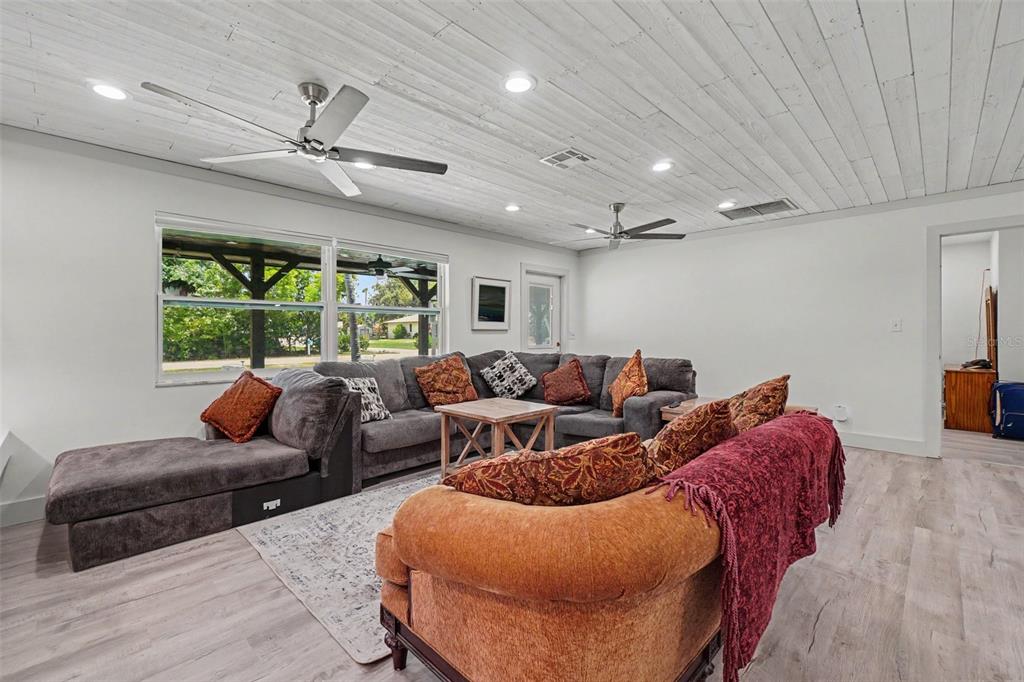 A living room features a sectional sofa, a patterned couch, and a white wood-plank ceiling — 3728 GASPARILLA STREET, ST JAMES CITY, FL