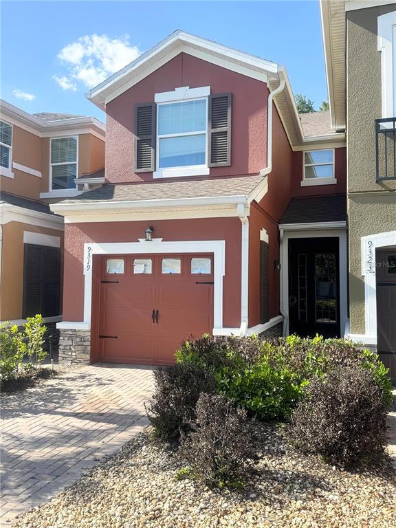 A two-story house with a red stucco exterior, a single-car garage, and a paved driveway — 9319 STRONGBARK LANE, ORLANDO, FL