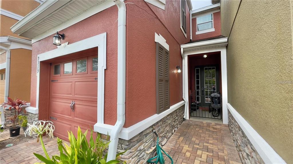 A red stucco house exterior features a garage, stone accents, and a covered front entryway — 9319 STRONGBARK LANE, ORLANDO, FL