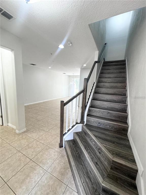 An interior view shows a tiled entryway leading to a living area and wooden stairs — 9319 STRONGBARK LANE, ORLANDO, FL