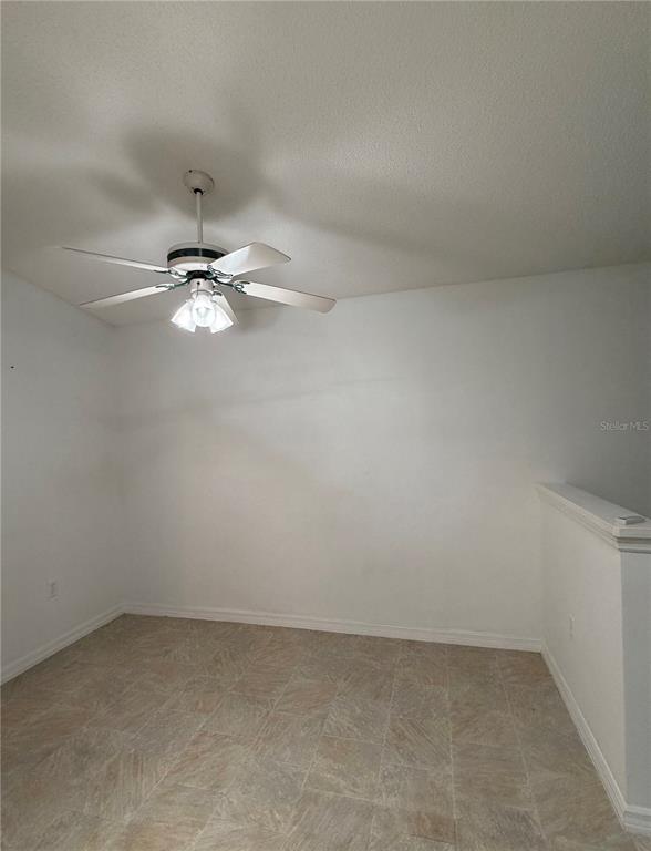 A room with white walls, tile flooring, and a ceiling fan with a light fixture — 6087 KITTIWAKE DRIVE, LAKELAND, FL