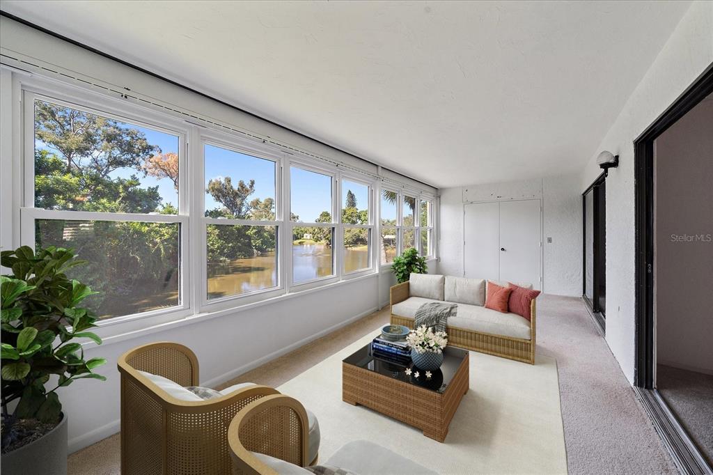 A sunroom features carpeted floors, wicker furniture, and large windows overlooking a body of water — 182 PINENEEDLE DRIVE, BRADENTON, FL