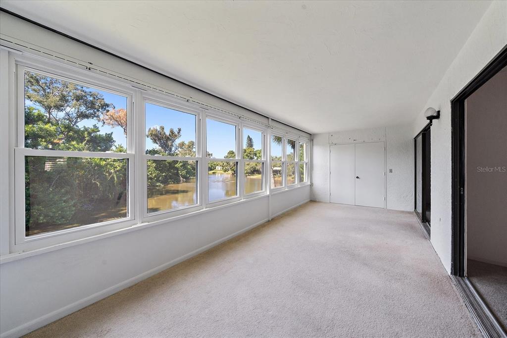 A sunroom with carpeted flooring, white walls, and large windows overlooking a body of water — 182 PINENEEDLE DRIVE, BRADENTON, FL
