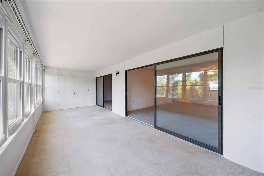 A sunroom with beige carpeting, white walls, and large sliding glass doors — 182 PINENEEDLE DRIVE, BRADENTON, FL