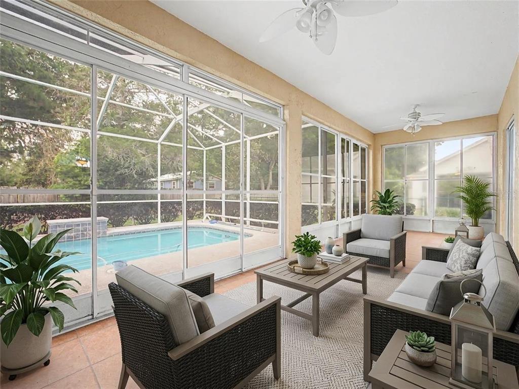 A sunroom with wicker furniture overlooks a screened-in swimming pool and backyard — 5455 NW 26TH LANE, OCALA, FL