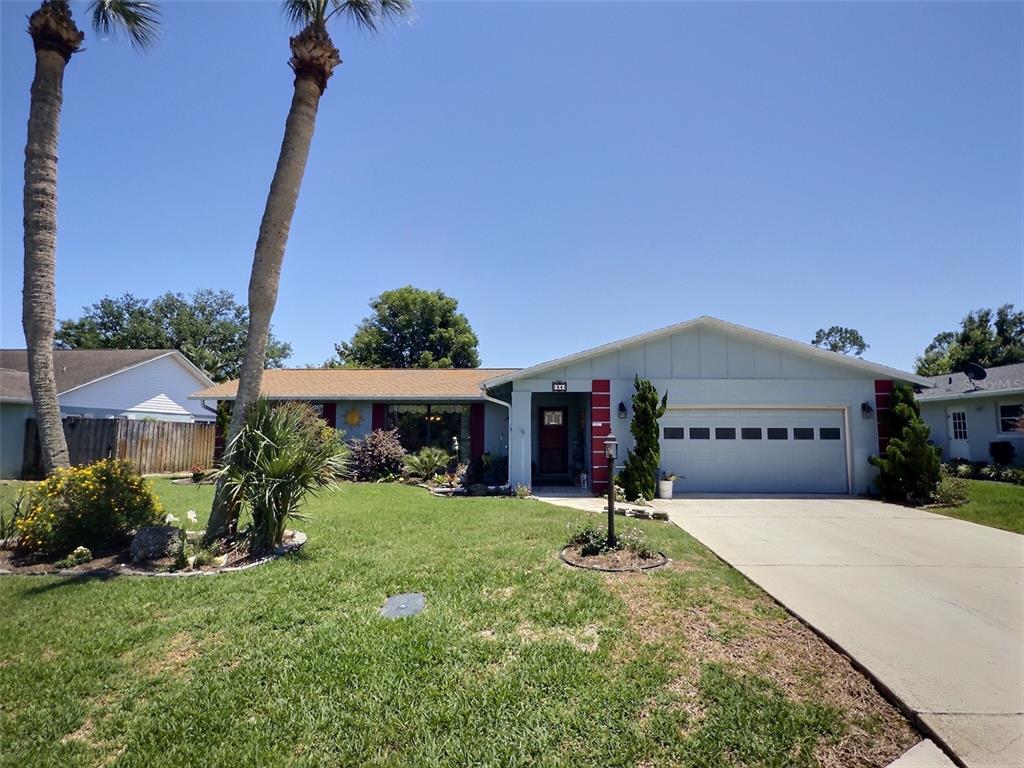 A light blue single-story house with a two-car garage and palm trees in the yard — 34 FELTER LANE, PALM COAST, FL