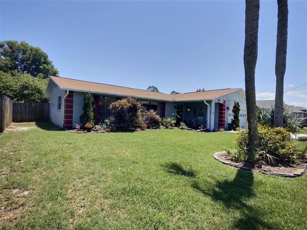 A single-story house with a light blue exterior, red trim, and a large front lawn — 34 FELTER LANE, PALM COAST, FL