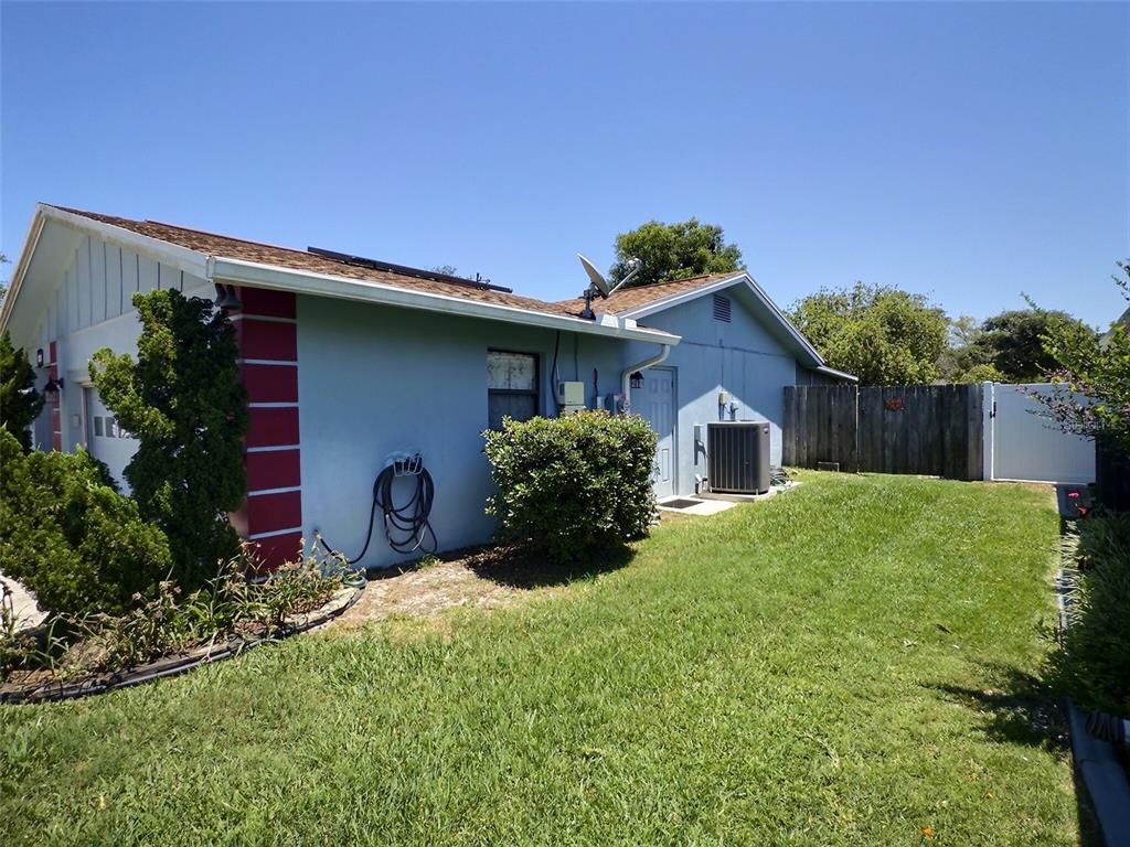 The exterior of a light blue house features a lawn, a fence, and an HVAC unit — 34 FELTER LANE, PALM COAST, FL