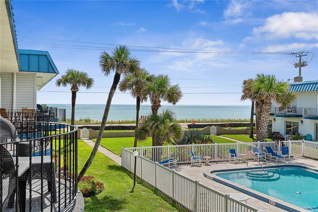 A view from a balcony overlooking a swimming pool, palm trees, and the ocean — 2750 OCEAN SHORE BOULEVARD UNIT 430, ORMOND BEACH, FL