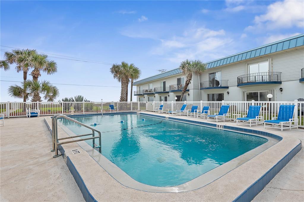 An outdoor swimming pool is surrounded by a white fence and lounge chairs — 2750 OCEAN SHORE BOULEVARD UNIT 430, ORMOND BEACH, FL