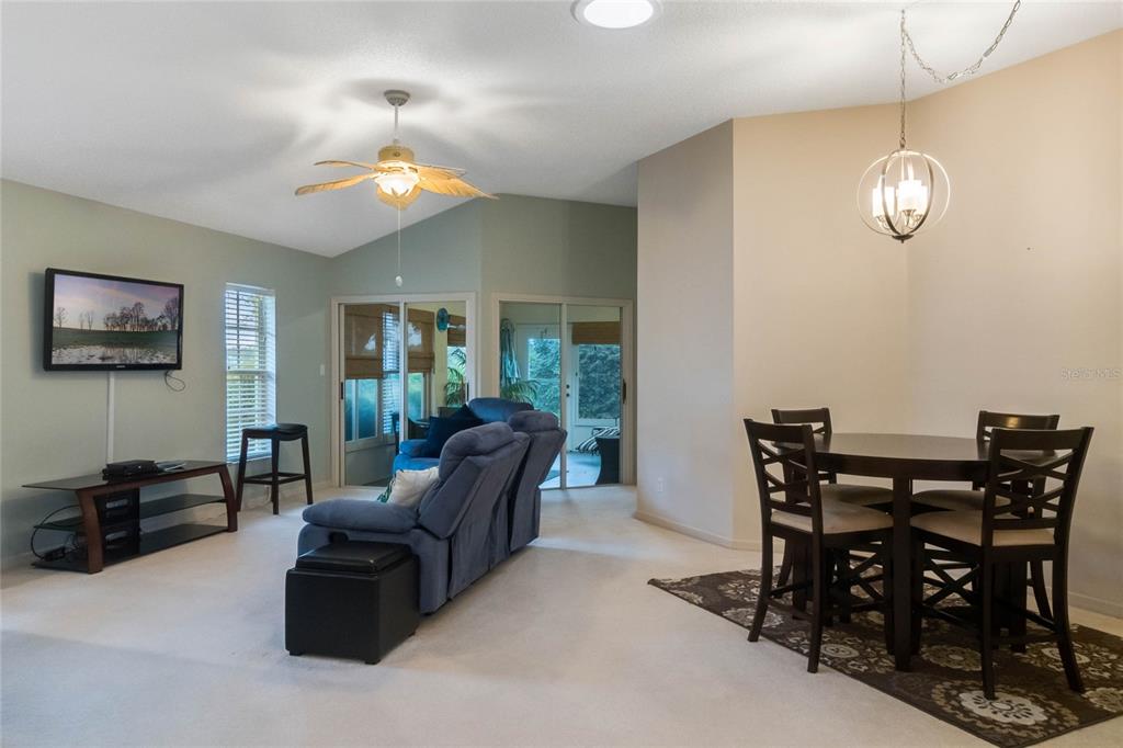 A living and dining area with a blue sofa, dining set, and sliding glass doors — 21721 KING RICHARDS WAY, LEESBURG, FL