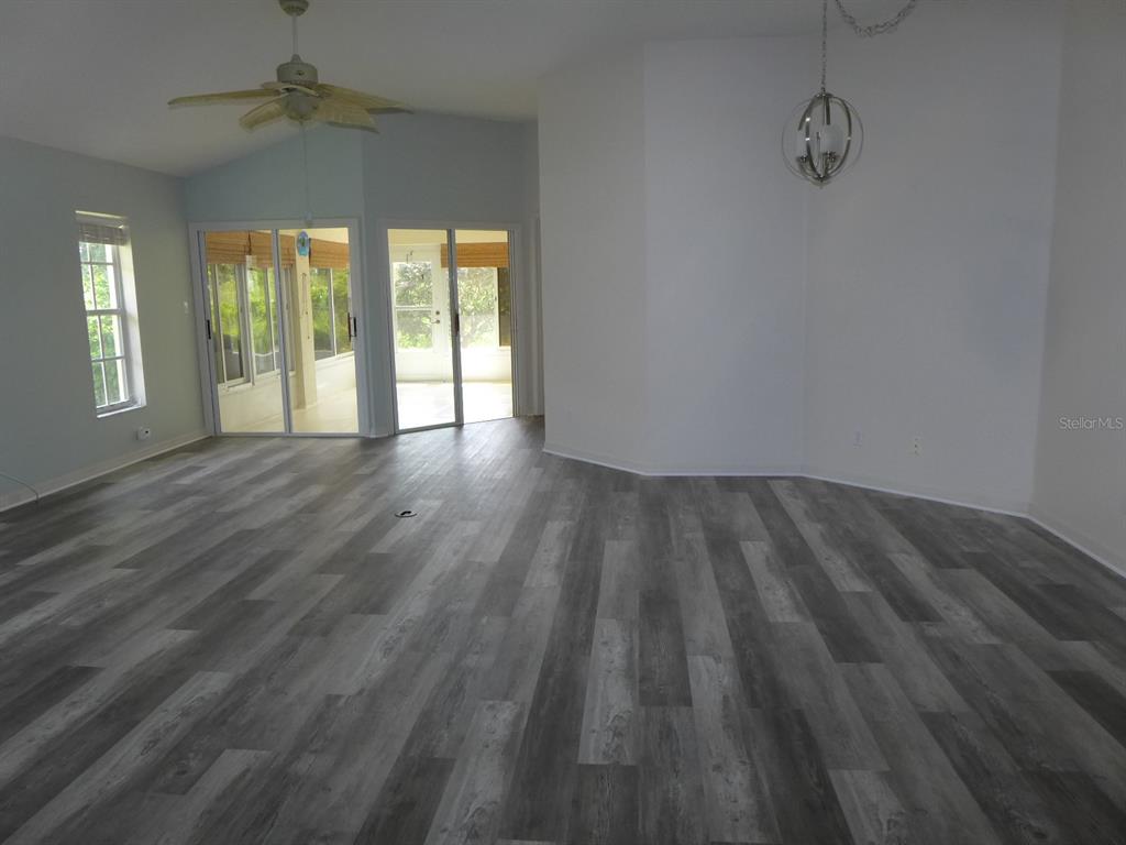 An open living area features gray wood-look flooring, a ceiling fan, and sliding glass doors — 21721 KING RICHARDS WAY, LEESBURG, FL