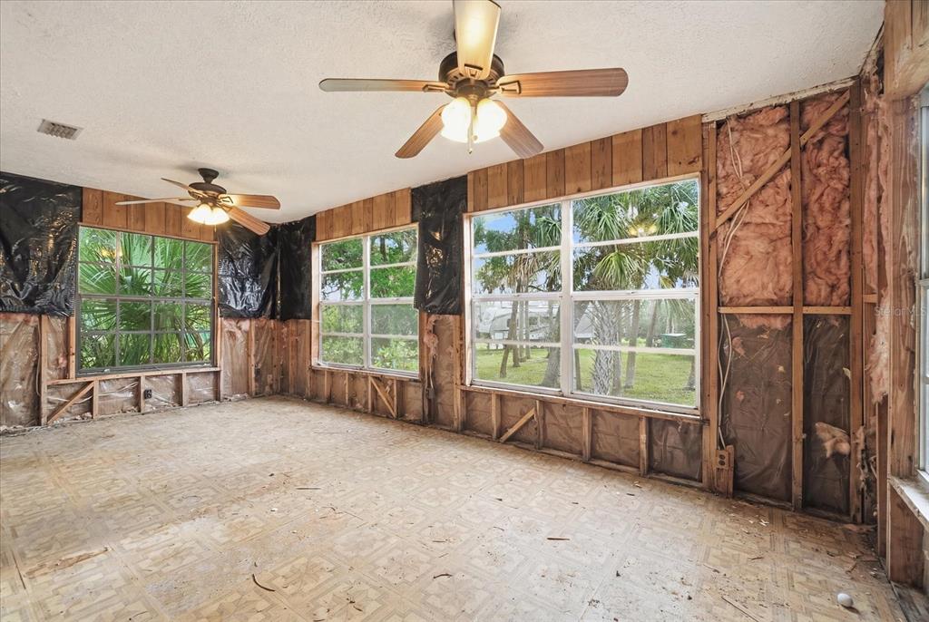An unfinished room features exposed wall studs, fiberglass insulation, vinyl flooring, and two ceiling fans — 14496 & 14498 W CAPTAIN COURT, CRYSTAL RIVER, FL
