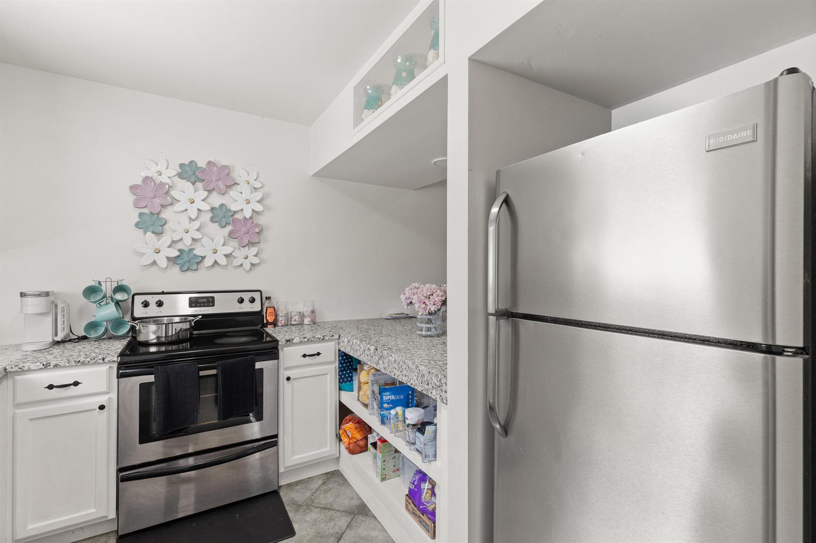 A kitchen features stainless steel appliances, white cabinets, granite countertops, and open shelving — 1329 Villa Lane # 45, FL 32712, FL
