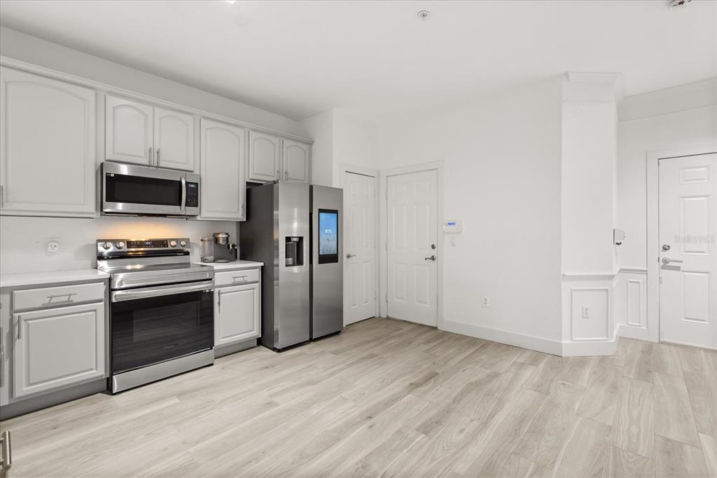 A kitchen features light gray cabinets, stainless steel appliances, and light wood-look flooring — 2804 POLVADERO LANE UNIT 103, ORLANDO, FL