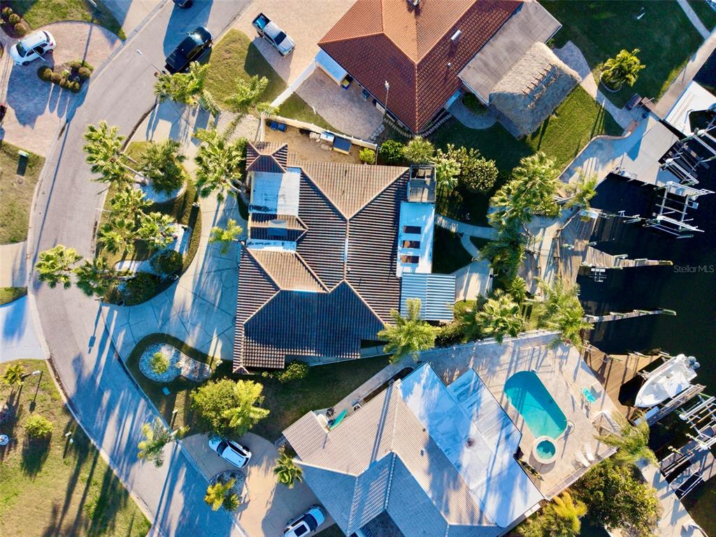 An aerial view shows two waterfront houses with tiled roofs, swimming pools, and boat docks — 4951 GALLEON COURT, NEW PORT RICHEY, FL