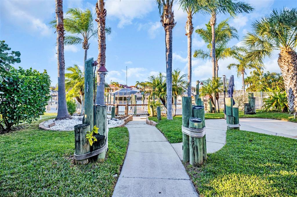 A concrete walkway leads through a grassy yard toward a boat dock and canal — 4951 GALLEON COURT, NEW PORT RICHEY, FL