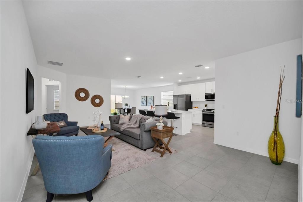 An open-concept living room and kitchen featuring gray tile floors, white cabinets, and blue furniture — 1154 OAK BLUFF DRIVE, DAVENPORT, FL