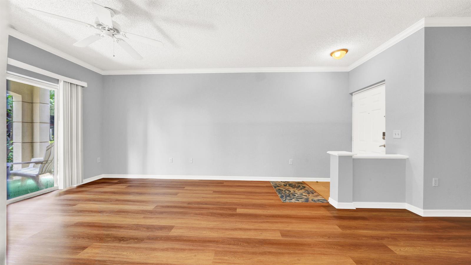An empty living room features light gray walls, wood-look flooring, a ceiling fan, and sliding doors — 3106 Tuscany Way, Boynton Beach FL 33435, BOYNTON BEACH, FL