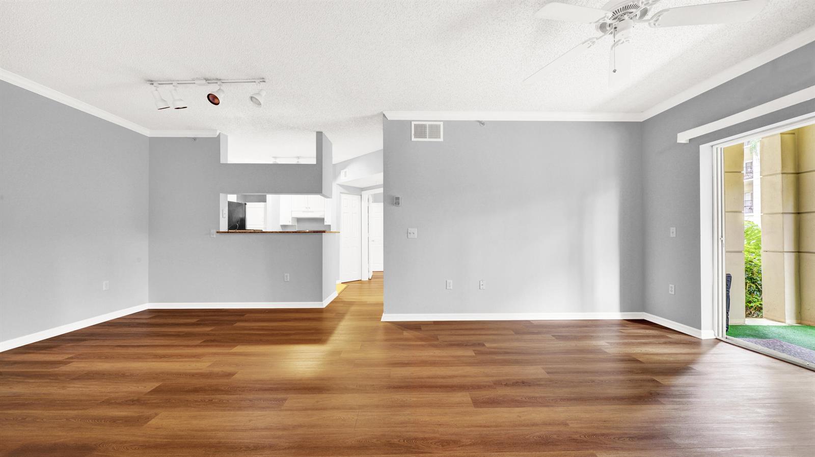 An empty living room with light gray walls, wood-look flooring, and a sliding glass door — 3106 Tuscany Way, Boynton Beach FL 33435, BOYNTON BEACH, FL