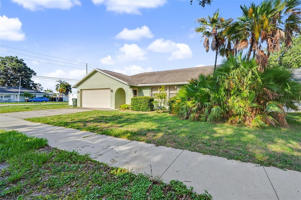 A single-story house with a light green exterior, a two-car garage, and large palm trees — 12543 108TH STREET, LARGO, FL