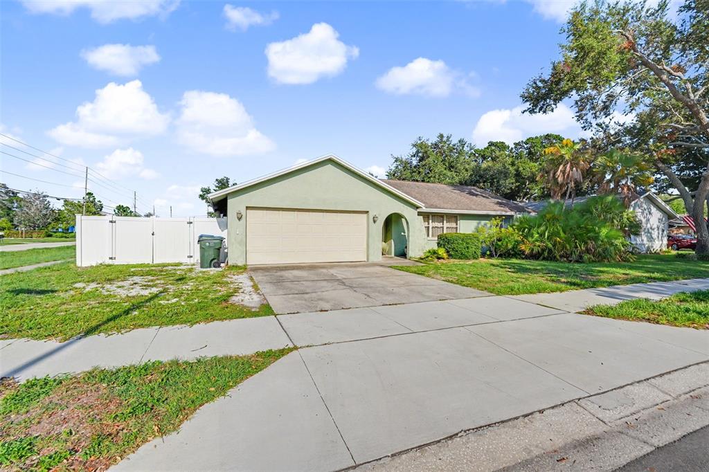 A light green single-story house with a two-car garage and a white privacy fence — 12543 108TH STREET, LARGO, FL