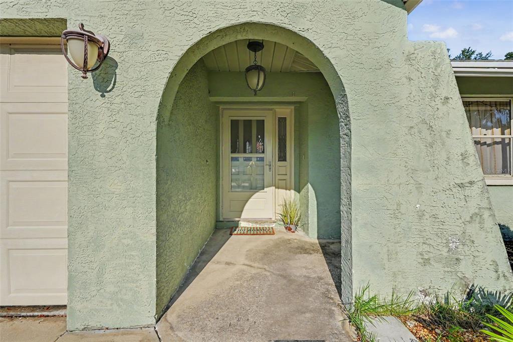 The exterior of a house features a green stucco facade with an arched entryway — 12543 108TH STREET, LARGO, FL