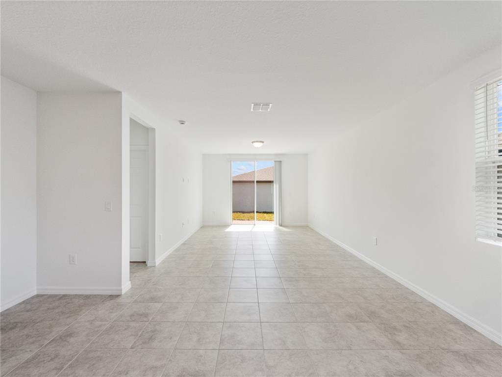 An empty room with white walls, light tile flooring, and a sliding glass door — 2606 IRISH ELK AVENUE, DAVENPORT, FL