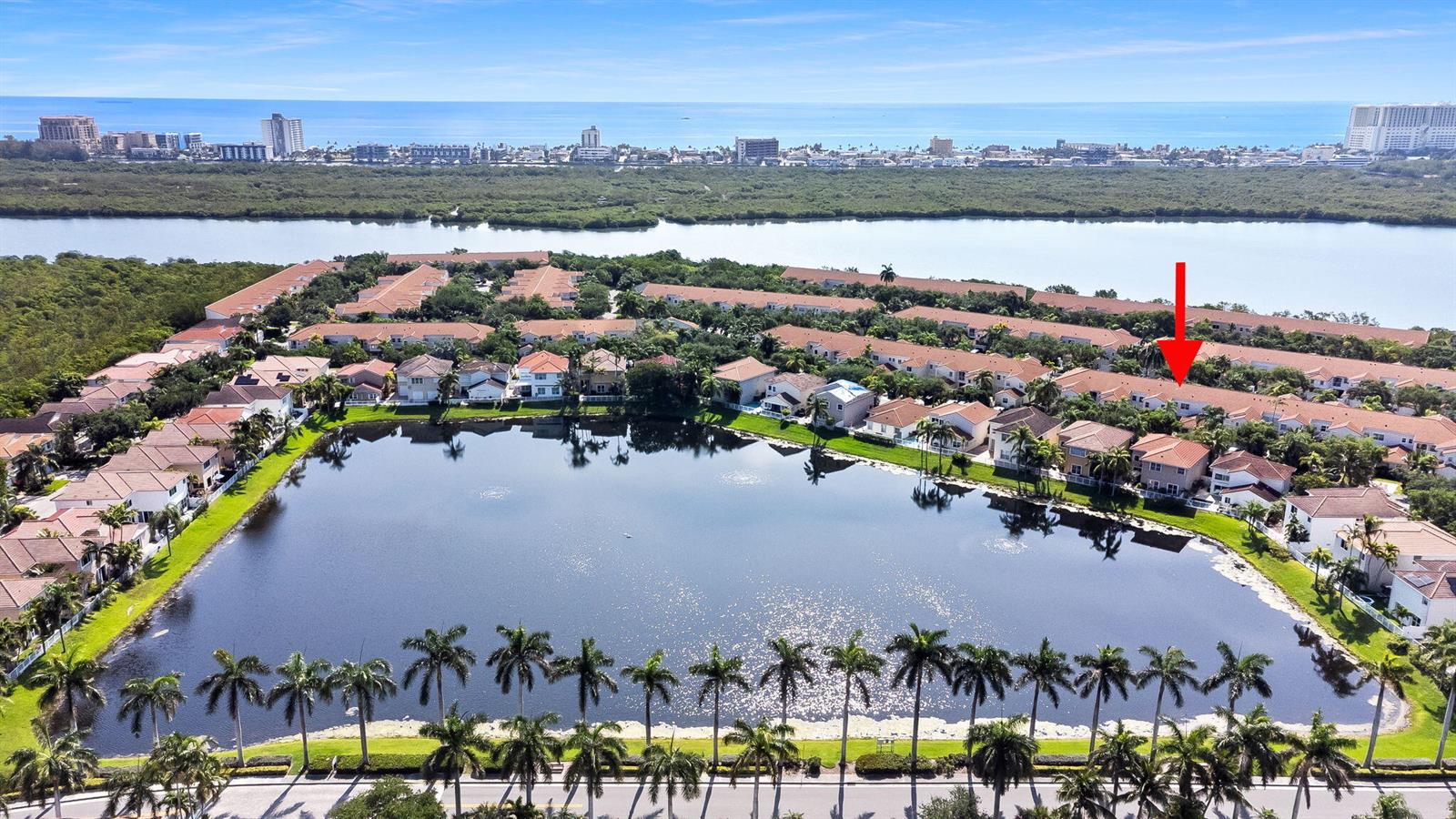 An aerial view shows a residential community with townhouses surrounding a central lake — 1551 Seagrape Way, Hollywood FL 33019, HOLLYWOOD, FL