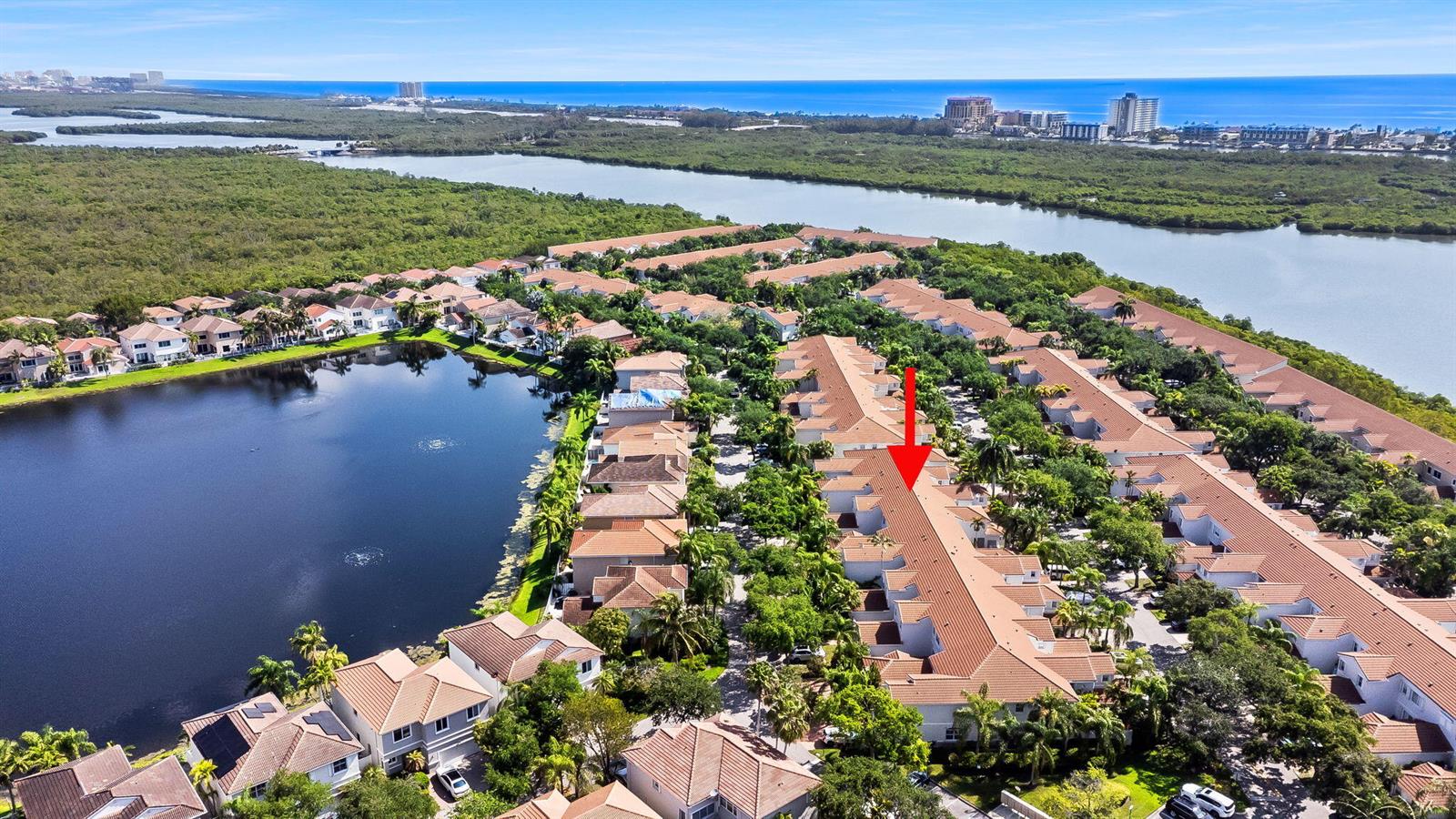 An aerial view shows a residential neighborhood with townhomes, a lake, and surrounding greenery — 1551 Seagrape Way, Hollywood FL 33019, HOLLYWOOD, FL
