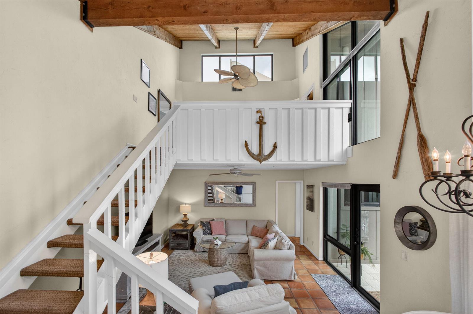A high-ceilinged living room features a staircase, a loft with an anchor, and tile floors — 1605 S Us Highway 1 # 14e, Jupiter FL 33477, JUPITER, FL