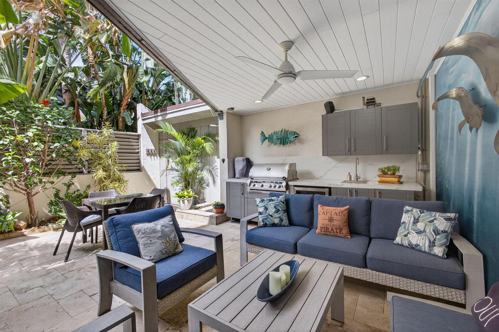 An outdoor patio features a covered kitchen area, blue seating, and a dining table — 1605 S Us Highway 1 # 14e, Jupiter FL 33477, JUPITER, FL