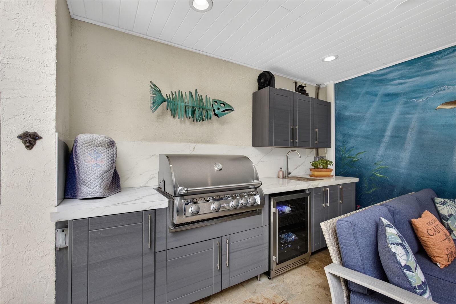 An outdoor kitchen features gray cabinets, a stainless steel grill, and a blue mural wall — 1605 S Us Highway 1 # 14e, Jupiter FL 33477, JUPITER, FL