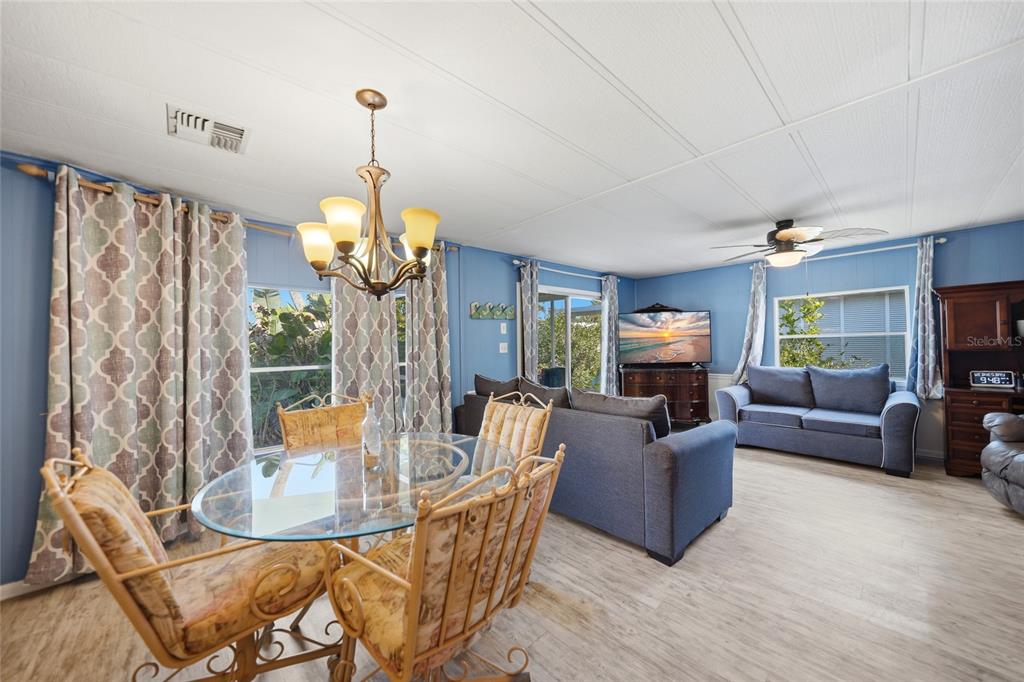 A living and dining area with blue walls, light wood flooring, and a glass table — 195 S FIJI CIRCLE, ENGLEWOOD, FL