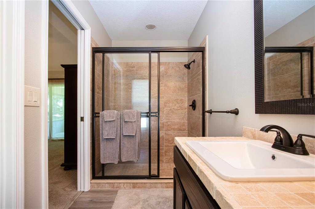 A bathroom features a tiled shower with a black frame, a vanity, and a mirror — 12341 WOOD SAGE TERRACE, BRADENTON, FL