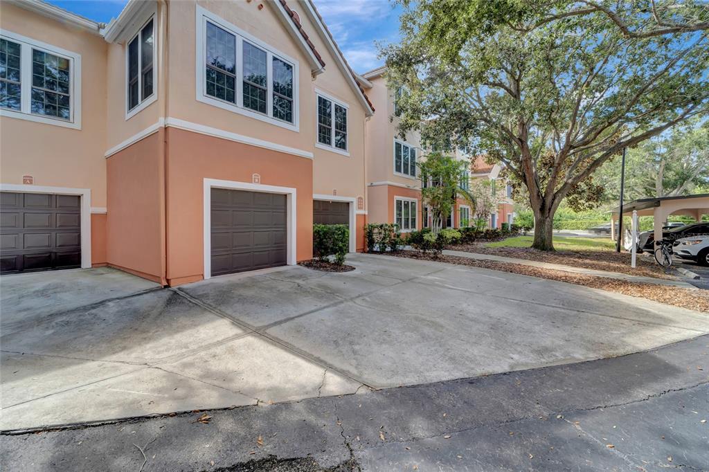 A multi-story townhouse exterior features tan and orange stucco walls with several brown garage doors — 4110 CENTRAL SARASOTA PARKWAY UNIT 125, SARASOTA, FL