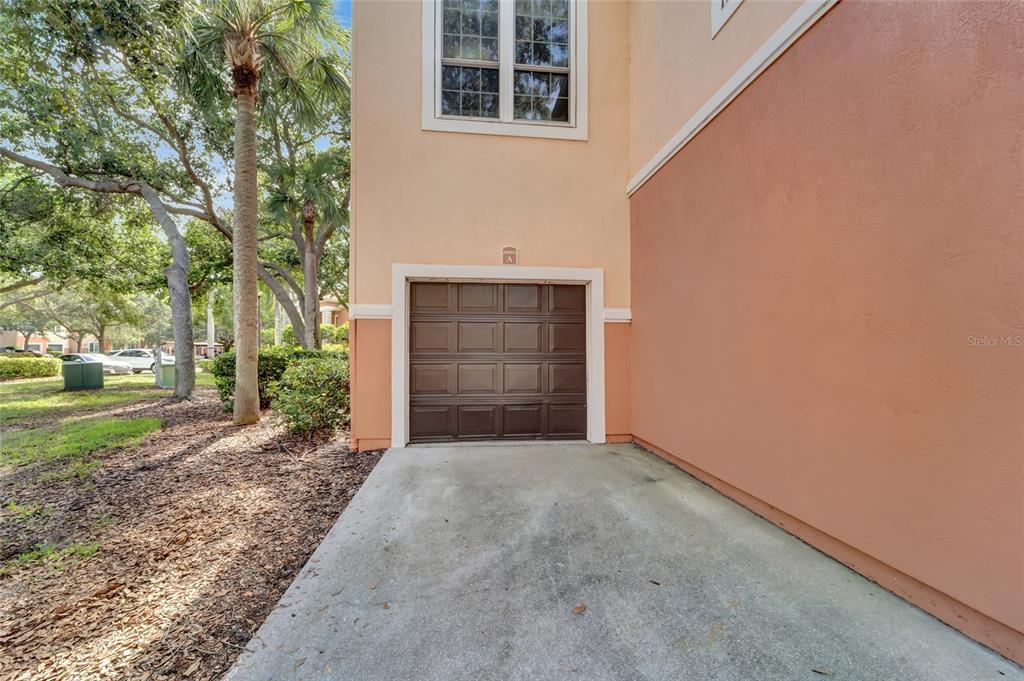 A single-car garage with a brown door is attached to a tan stucco building — 4110 CENTRAL SARASOTA PARKWAY UNIT 125, SARASOTA, FL